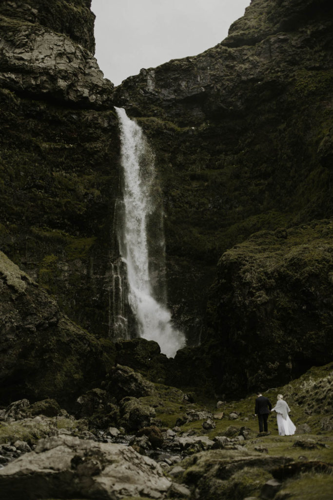 Iceland elopement couple climbing to the base of a giant waterfall