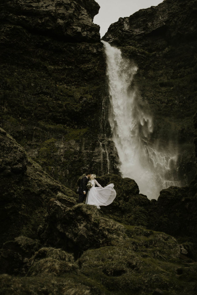 Iceland elopement photography with long and flowy wedding dress next to a waterfall