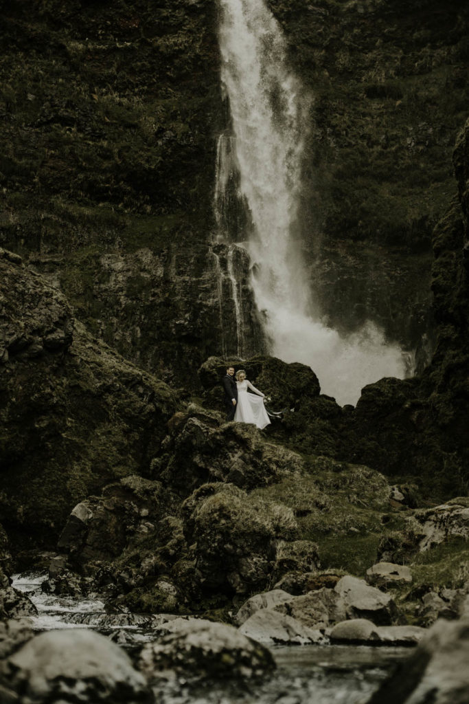 bride and groom next to waterfall in southern Iceland