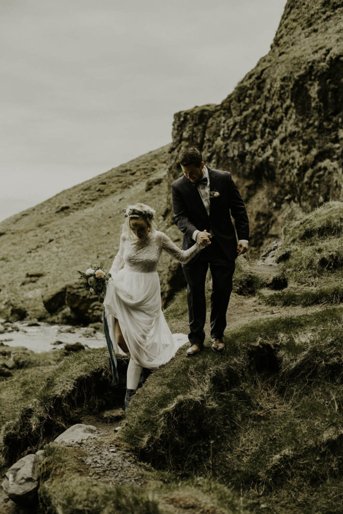 couple hiking down from a waterfall during an adventure elopement in Iceland