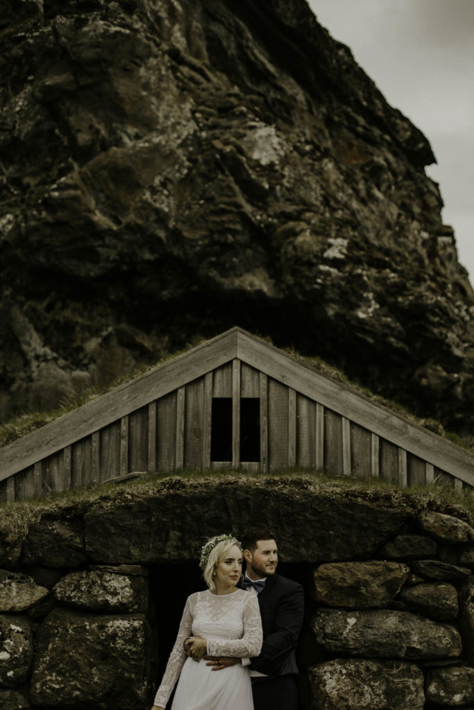 elopement couple in front of Icelandic home surrounded by mountains