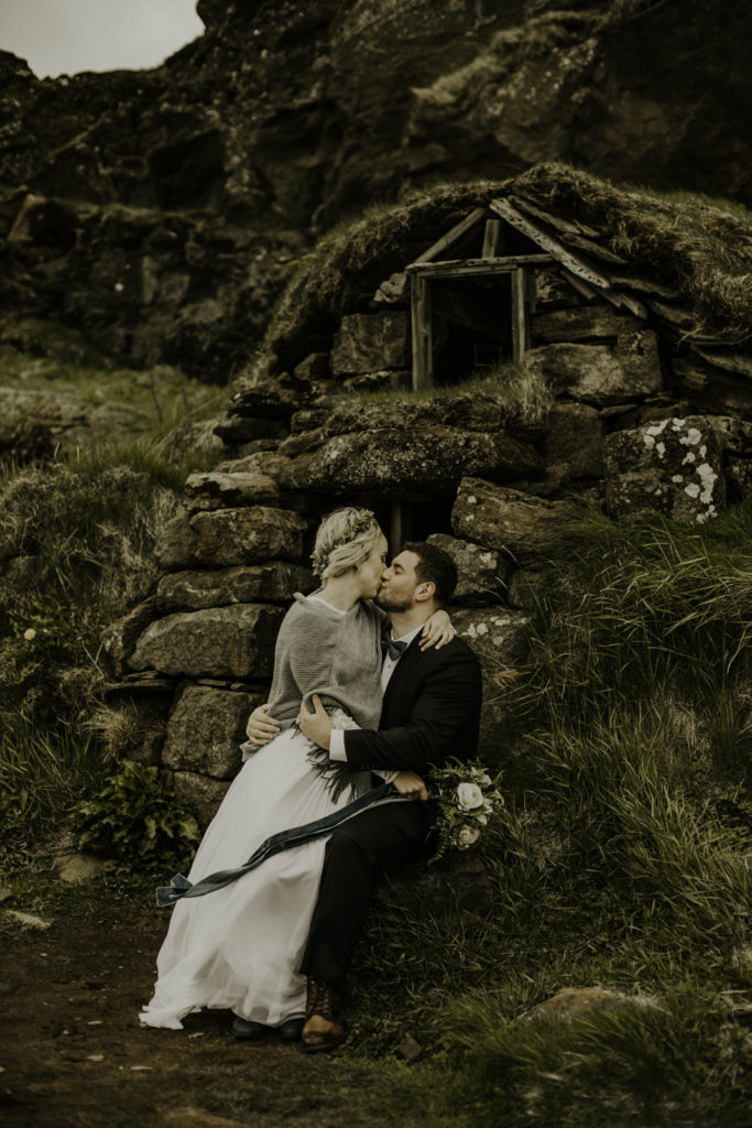 bride and groom in front of Icelandic home surrounded by mountains