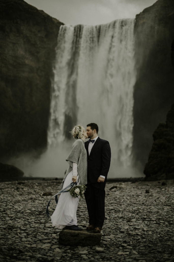 bride and groom looking at each other in front of waterfall