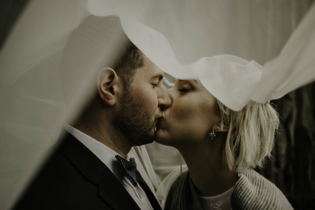 bride and groom kissing in veil