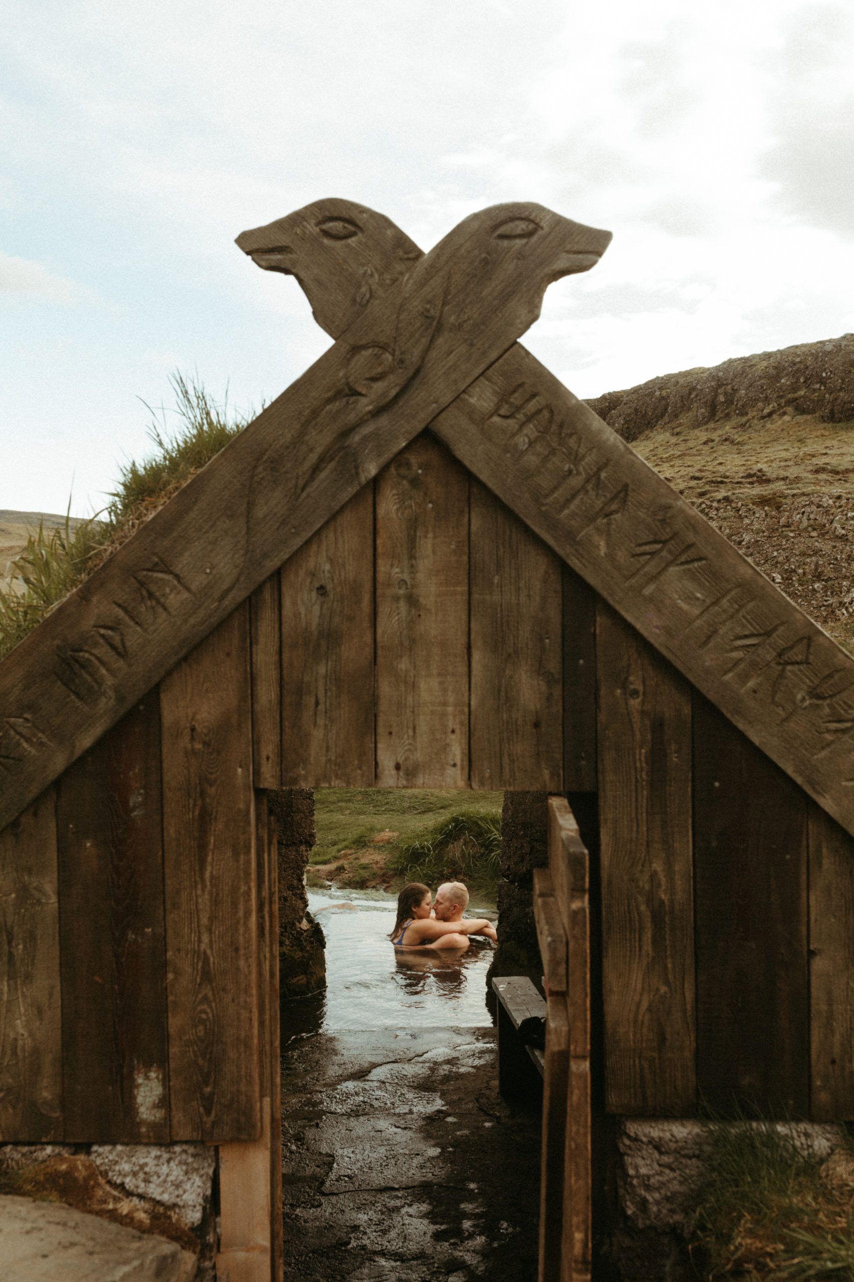 Couple soaking in iceland hot springs with viking hut. 