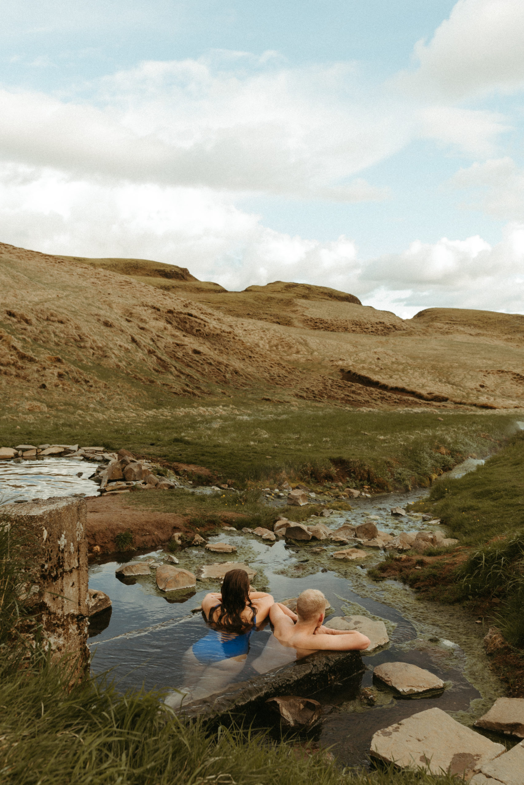 couple soaking in iceland hotsprings with a beautiful view of the mountains.