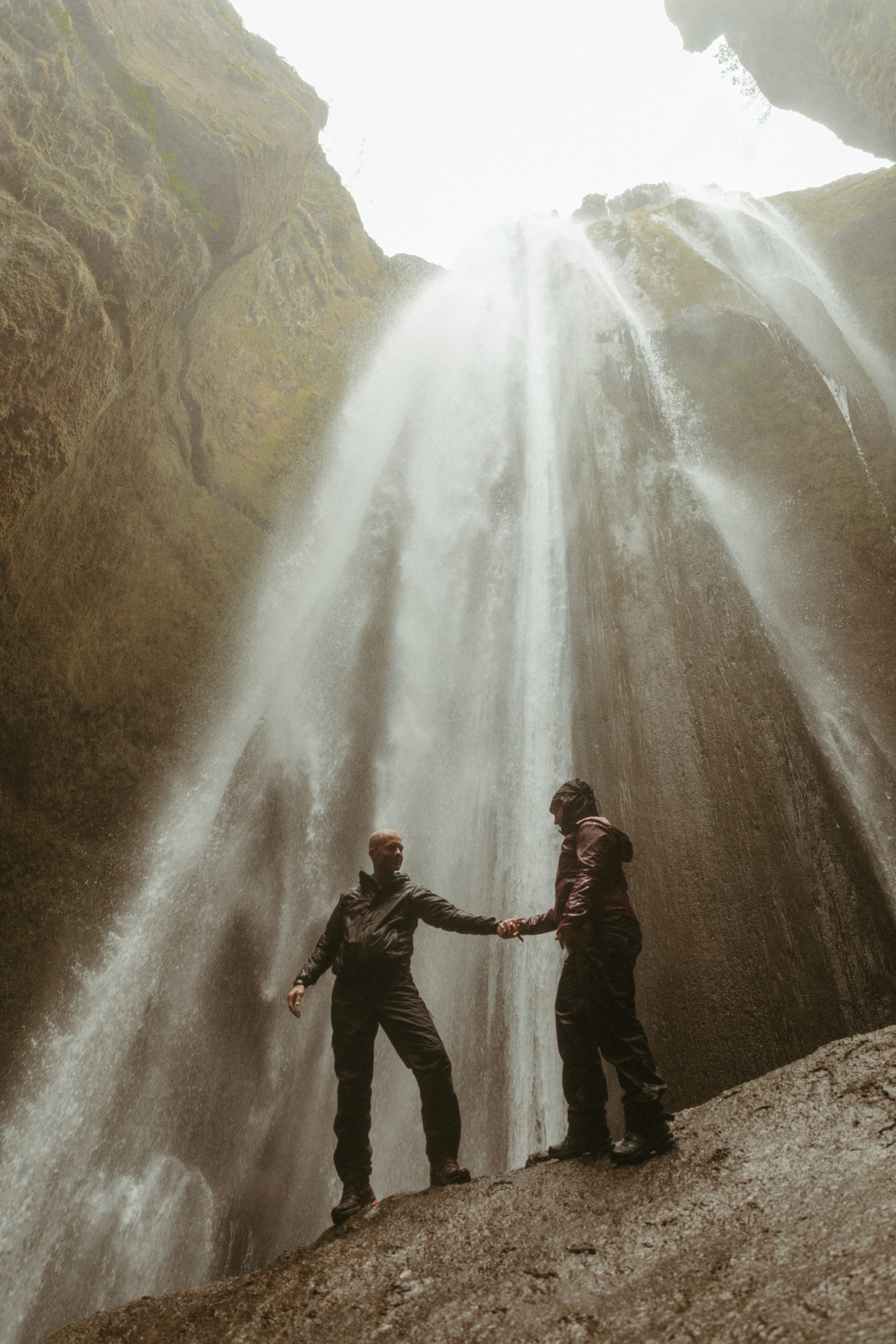 couple standing under waterfall in cave in Iceland.