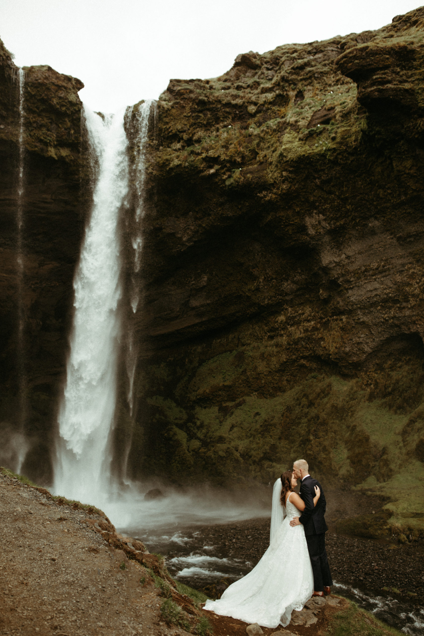 Bride and groom eloping in front of iceland waterfall. 