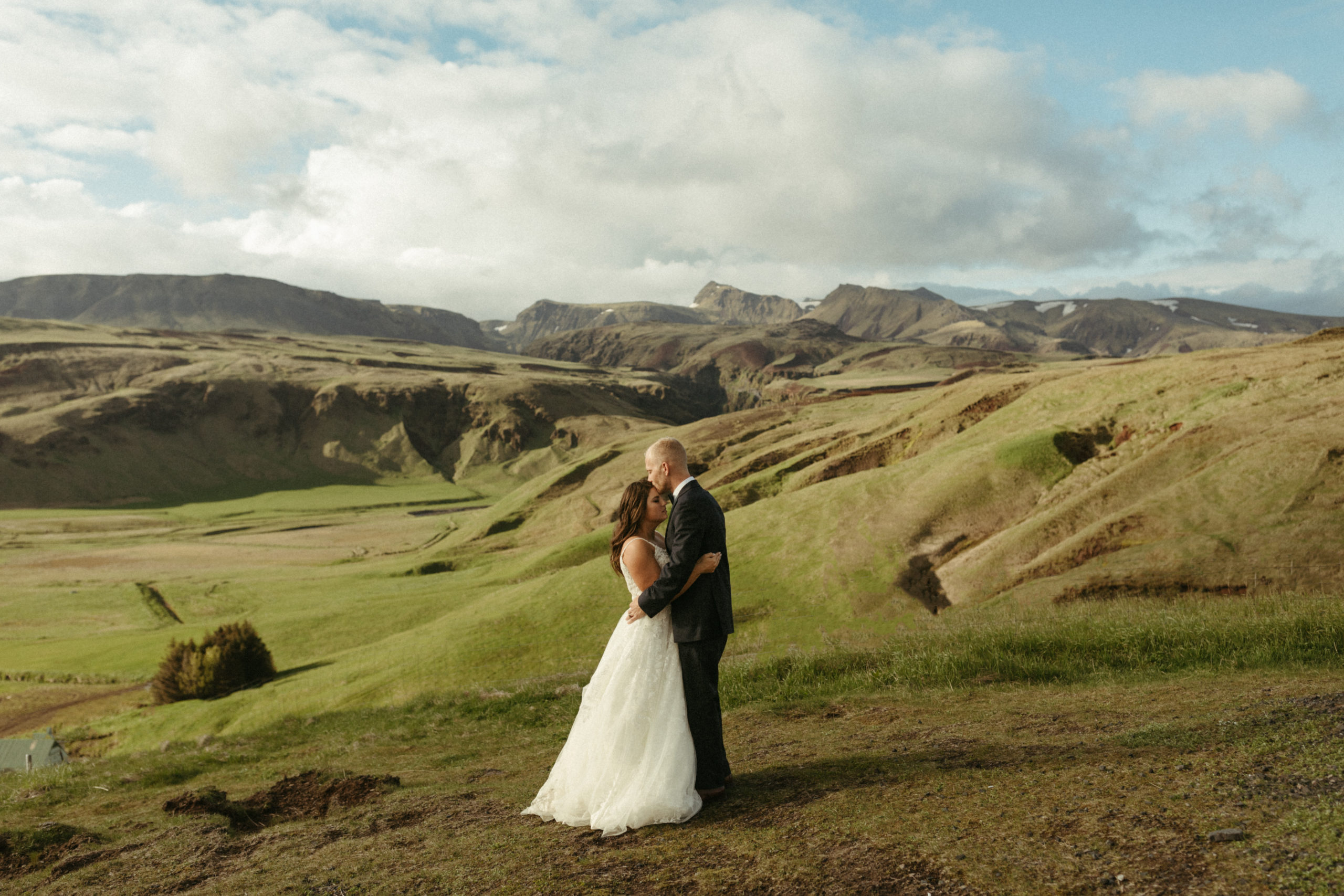 Bride and groom in iceland with mountains and green valleys behind them. 