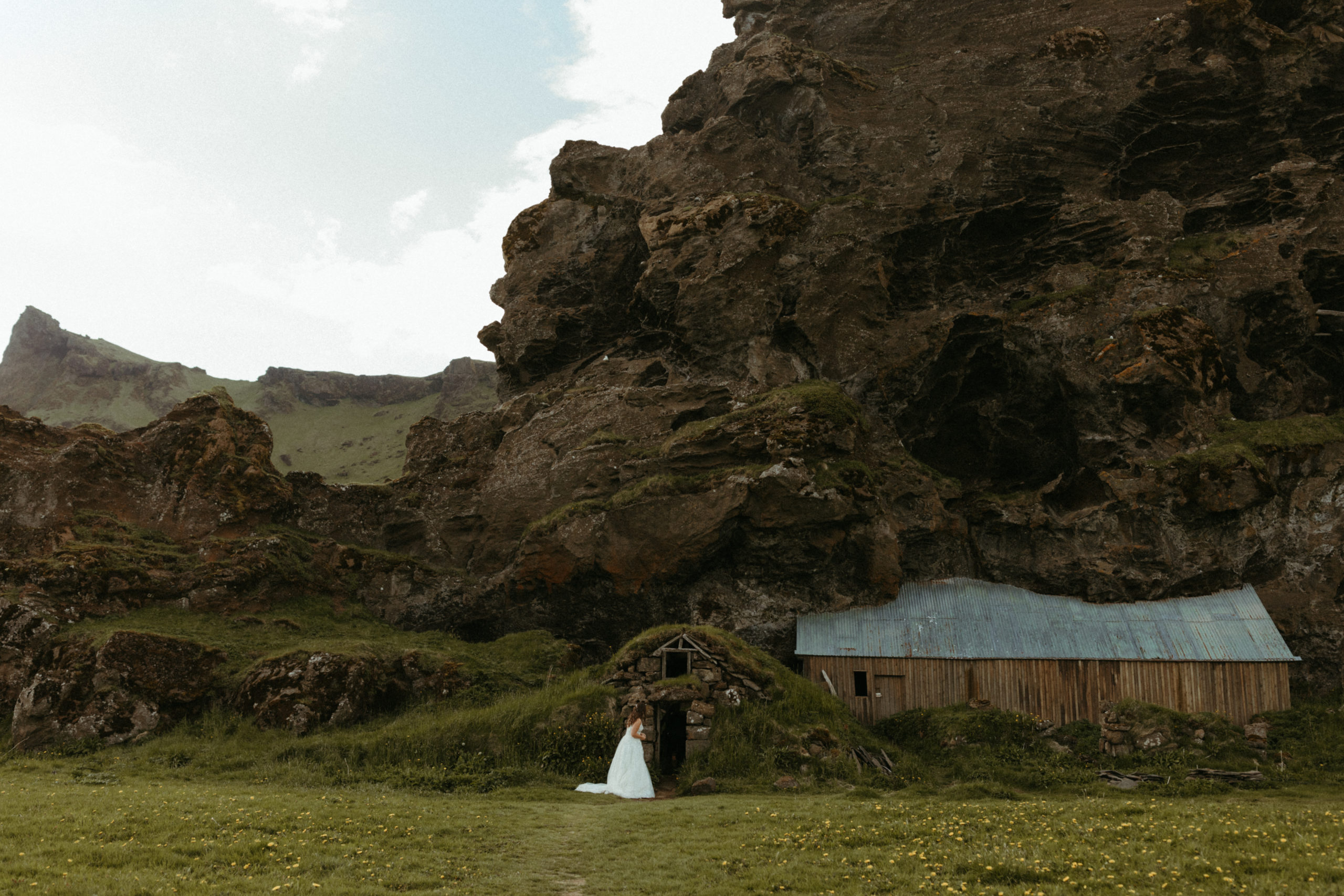 Bride in wedding dress looking into Iceland hobbit homes on wedding day. 