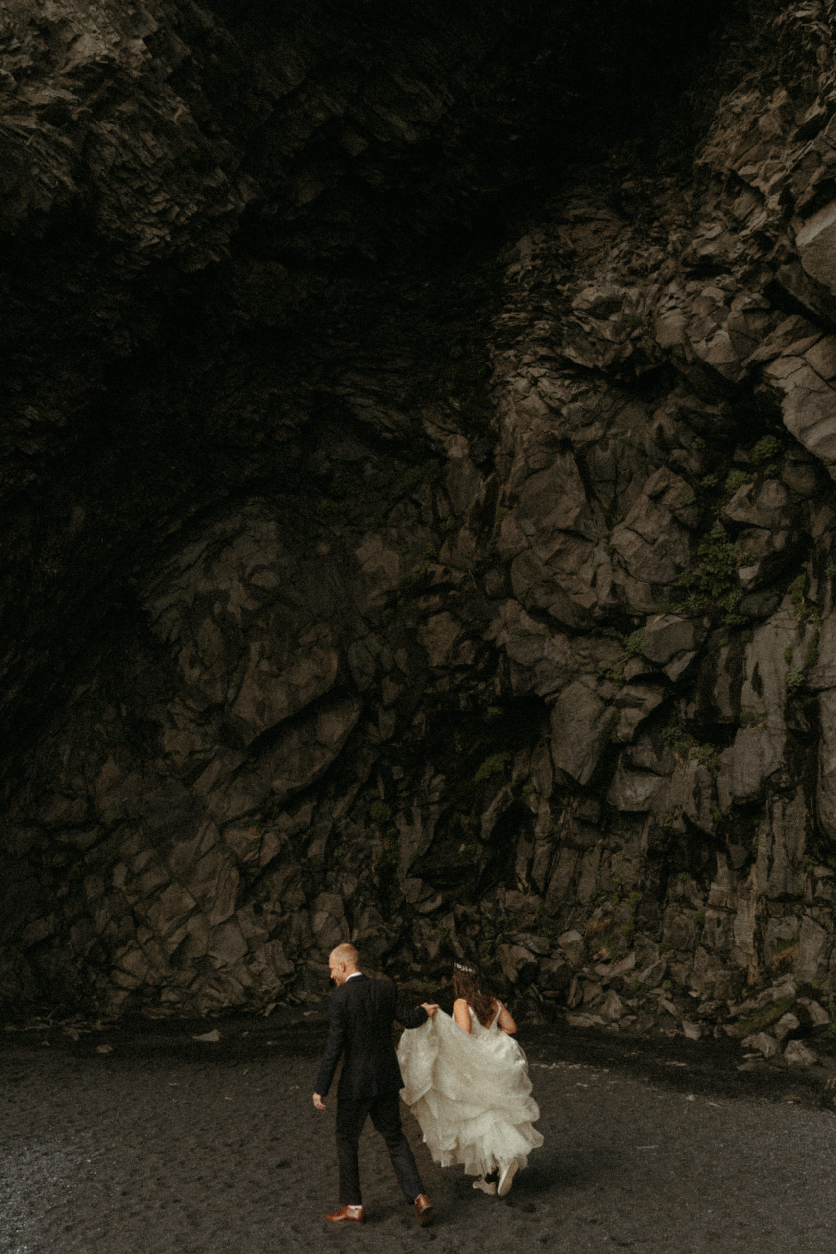 Bride and groom walking through Iceland cave on wedding day. 